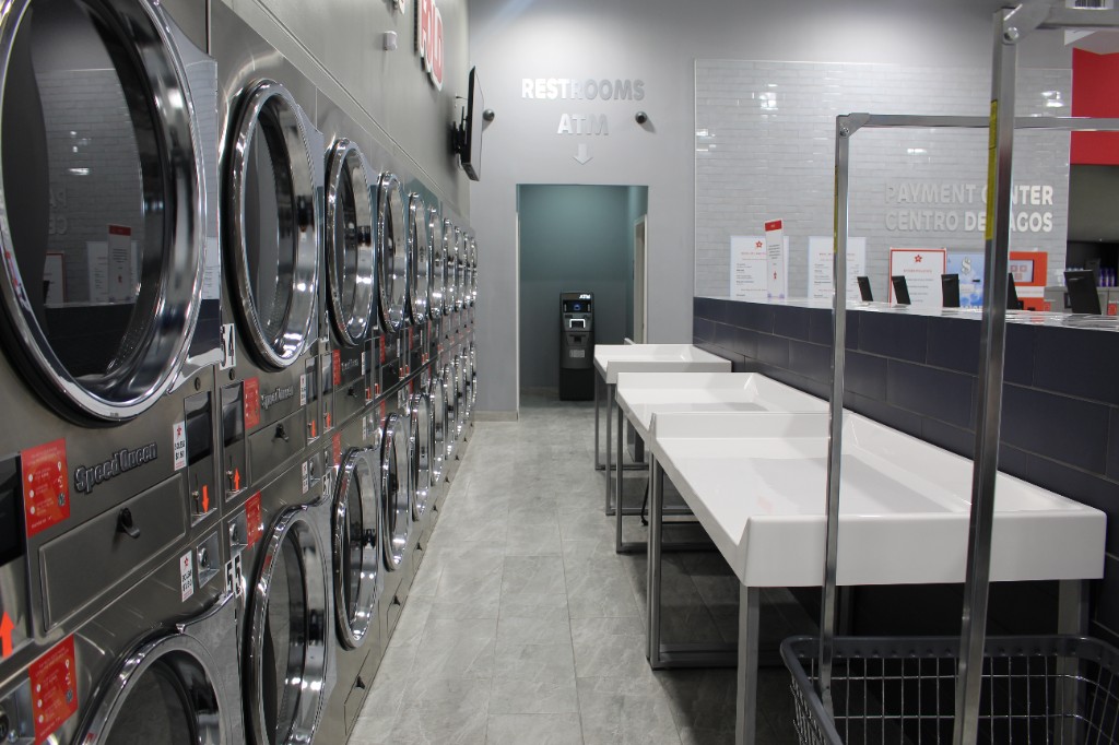 Dryers and white folding tables near restrooms and ATM