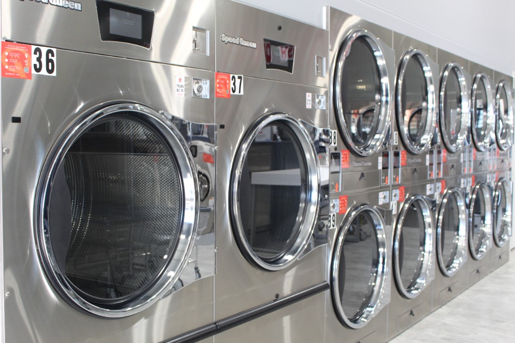 Stainless-steel washers and dryers in a bright aisle
